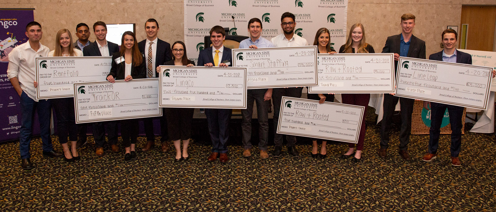 Business Model Competition winners standing with their oversized checks
